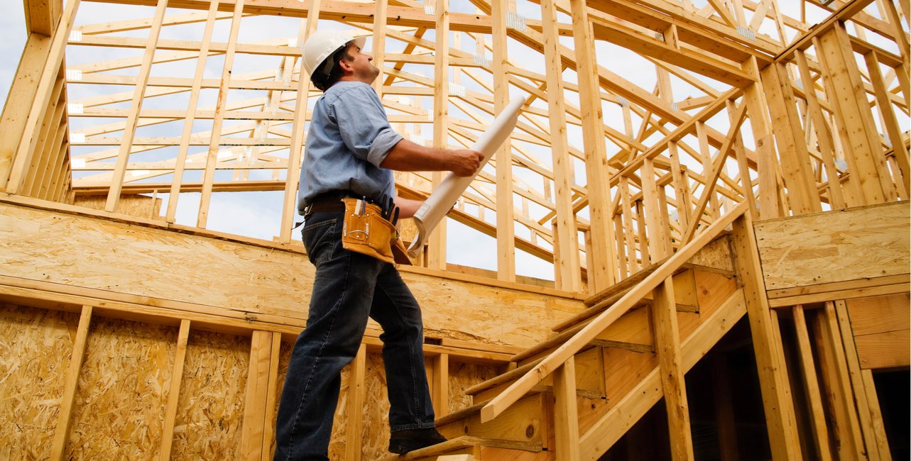 Worker walking with blueprints up stairs